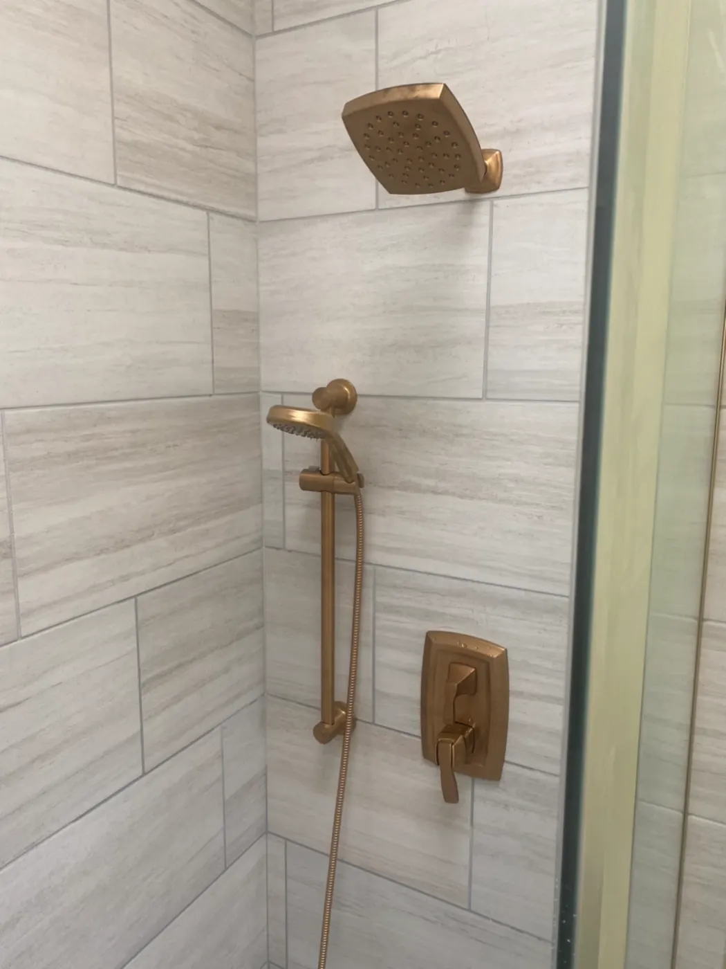 Tiled shower with brushed gold shower valve and handheld