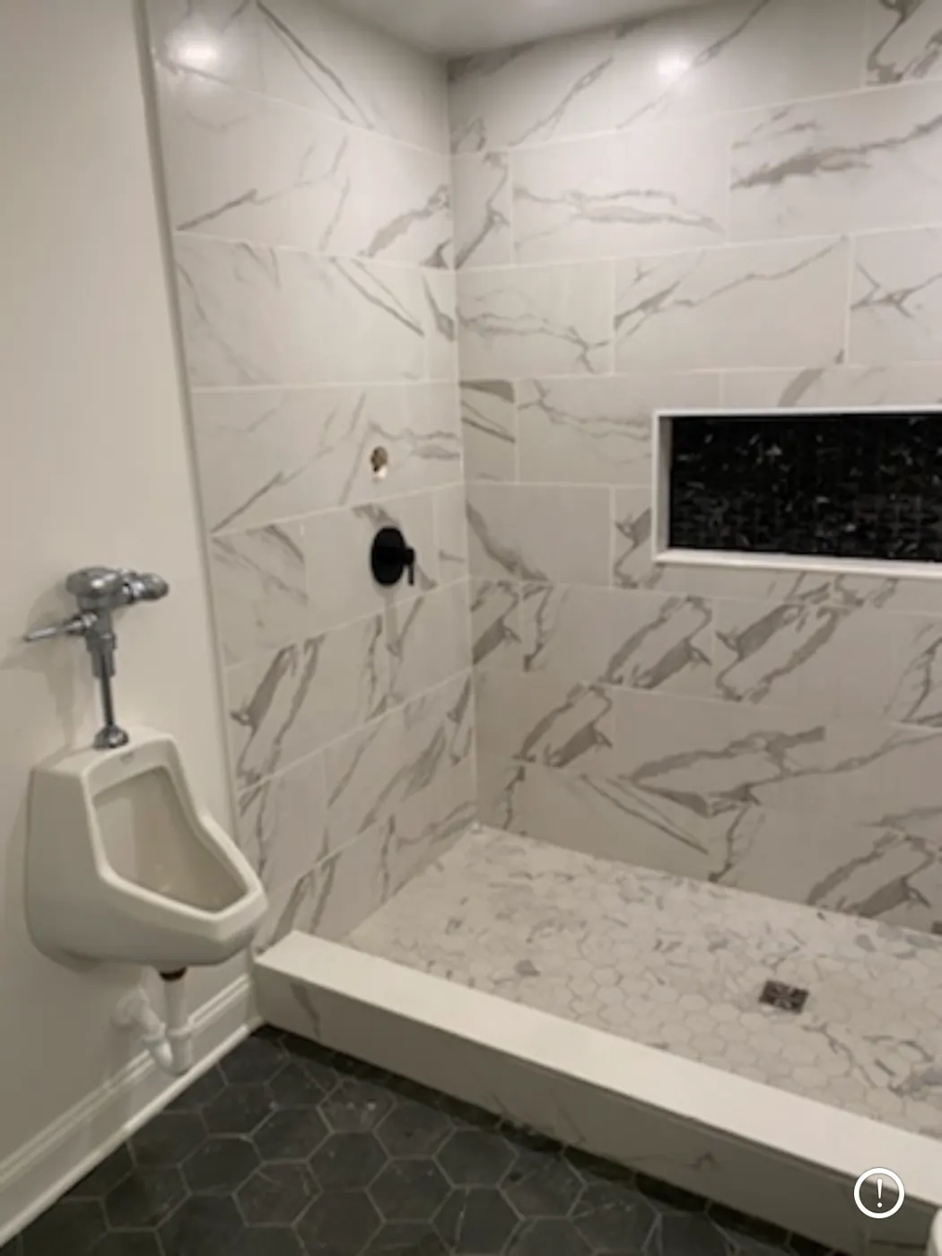 Marble-look tile shower with a black niche