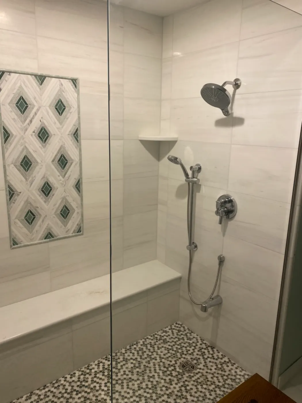 Tiled shower with a patterned accent and corner shelf