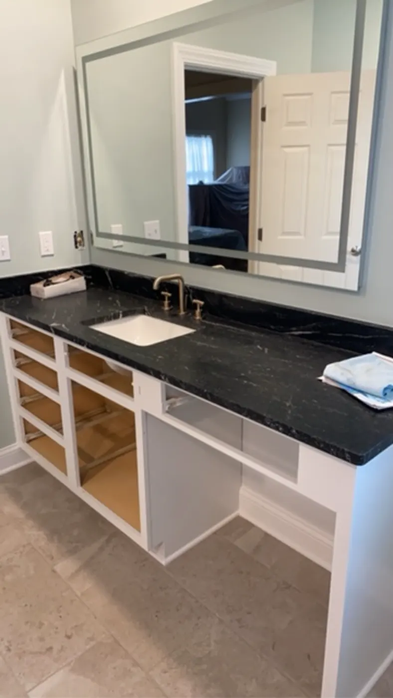 Double vanity with a black top and lighted mirror